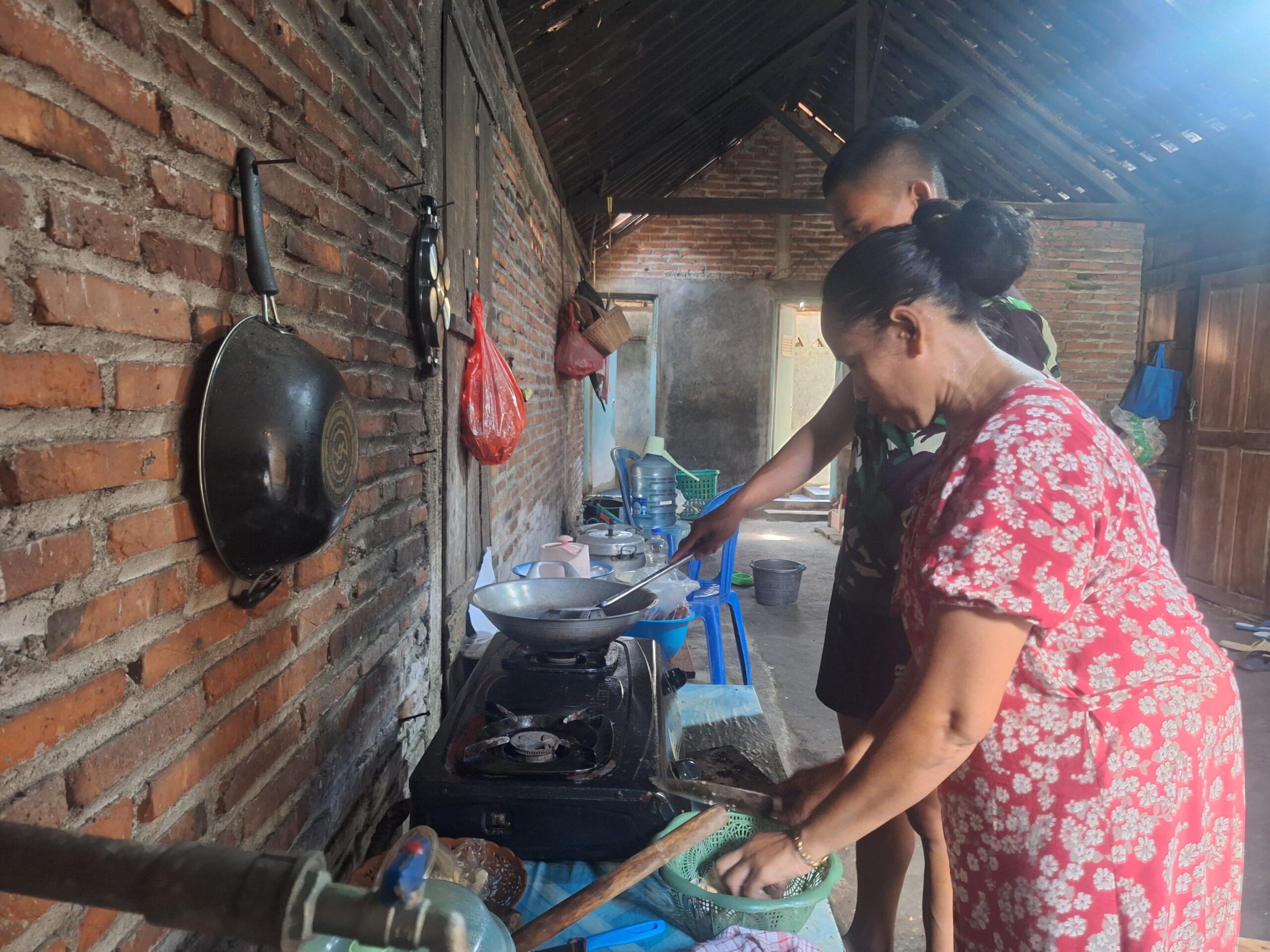 Anggota Satgas TMMD 128 Tak Canggung Bantu Ibu-Ibu Masak Di Dapur