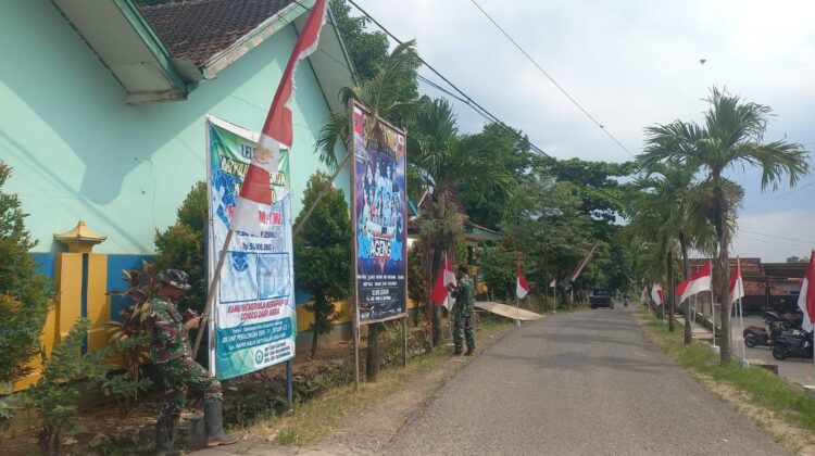 Persiapan Penutupan TMMD Reguler ke-128, Sertu Nursanto Pasang Umbul-Umbul di Lokasi Kegiatan